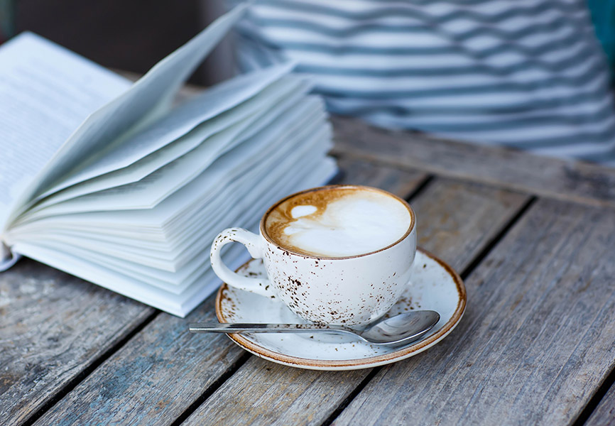 Latte on wooden table next to book